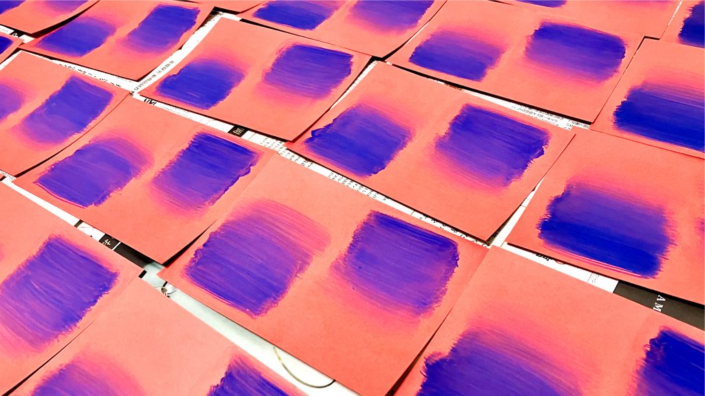 赤い紙に絵の具で青のグラデーションを描いた様子